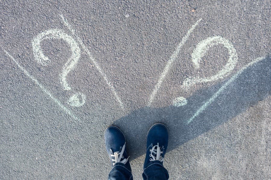 Woman standing near question marks written in chalk